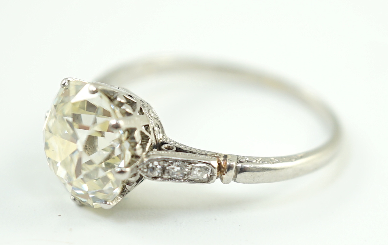 A mid 20th century platinum and single stone diamond ring, with six stone diamond chip set shoulders